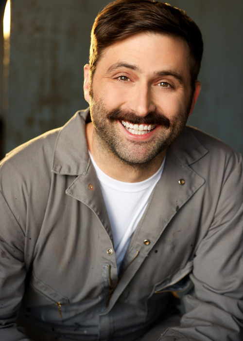 Headshot of Scott Rowan smiling, wearing a gray work jacket over a white T-shirt